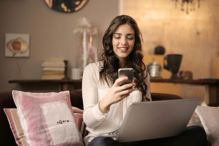 Vrouw zit met goede internetverbinding achter haar laptop en mobile telefoon
